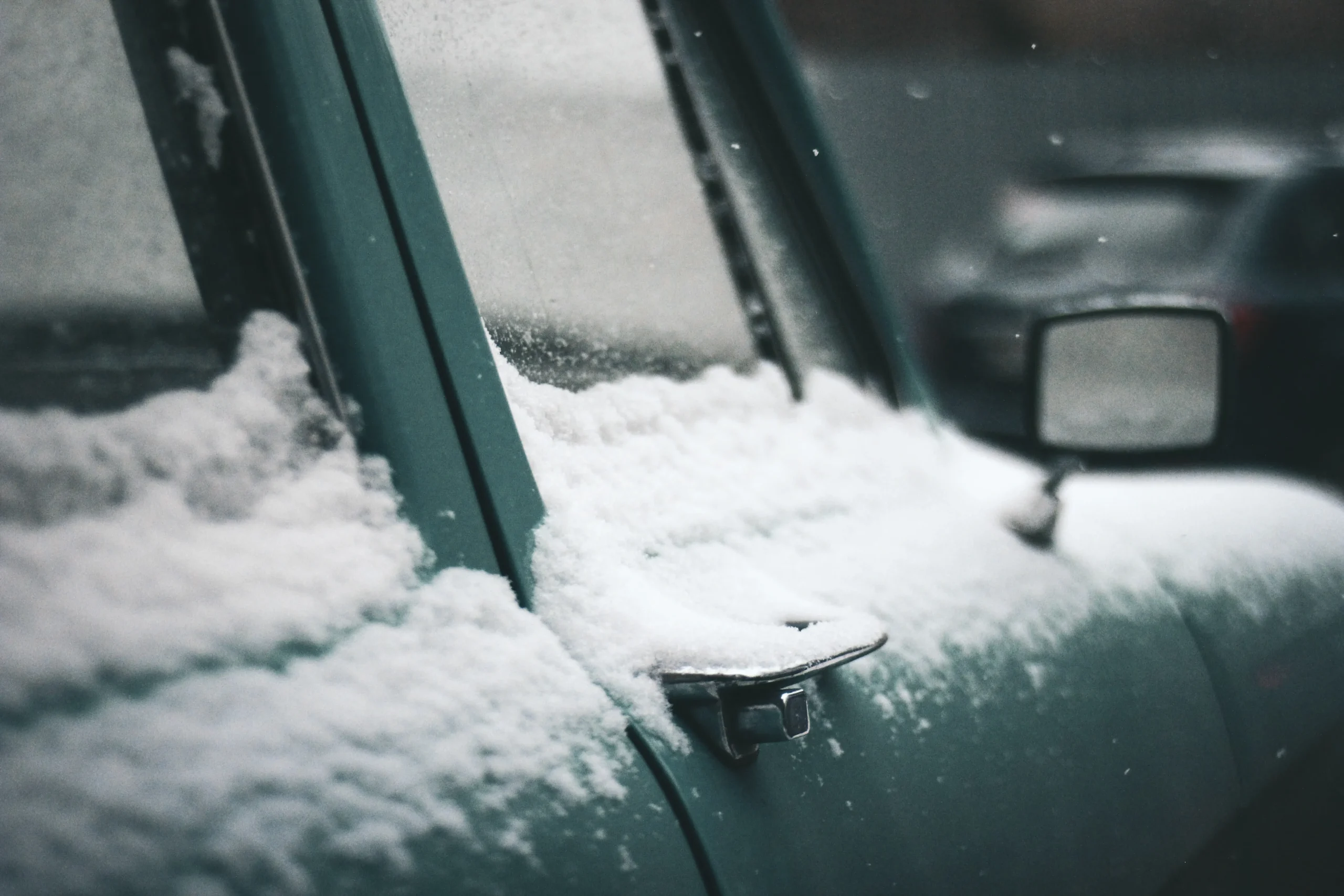 Close-up view of a car with snow-covered exterior, captured from a side door angle.